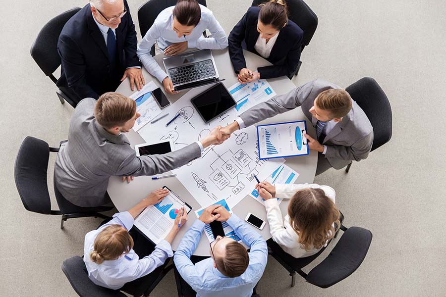 Business Insurance - Group of Employees Sitting Around Table in Office During Business Meeting